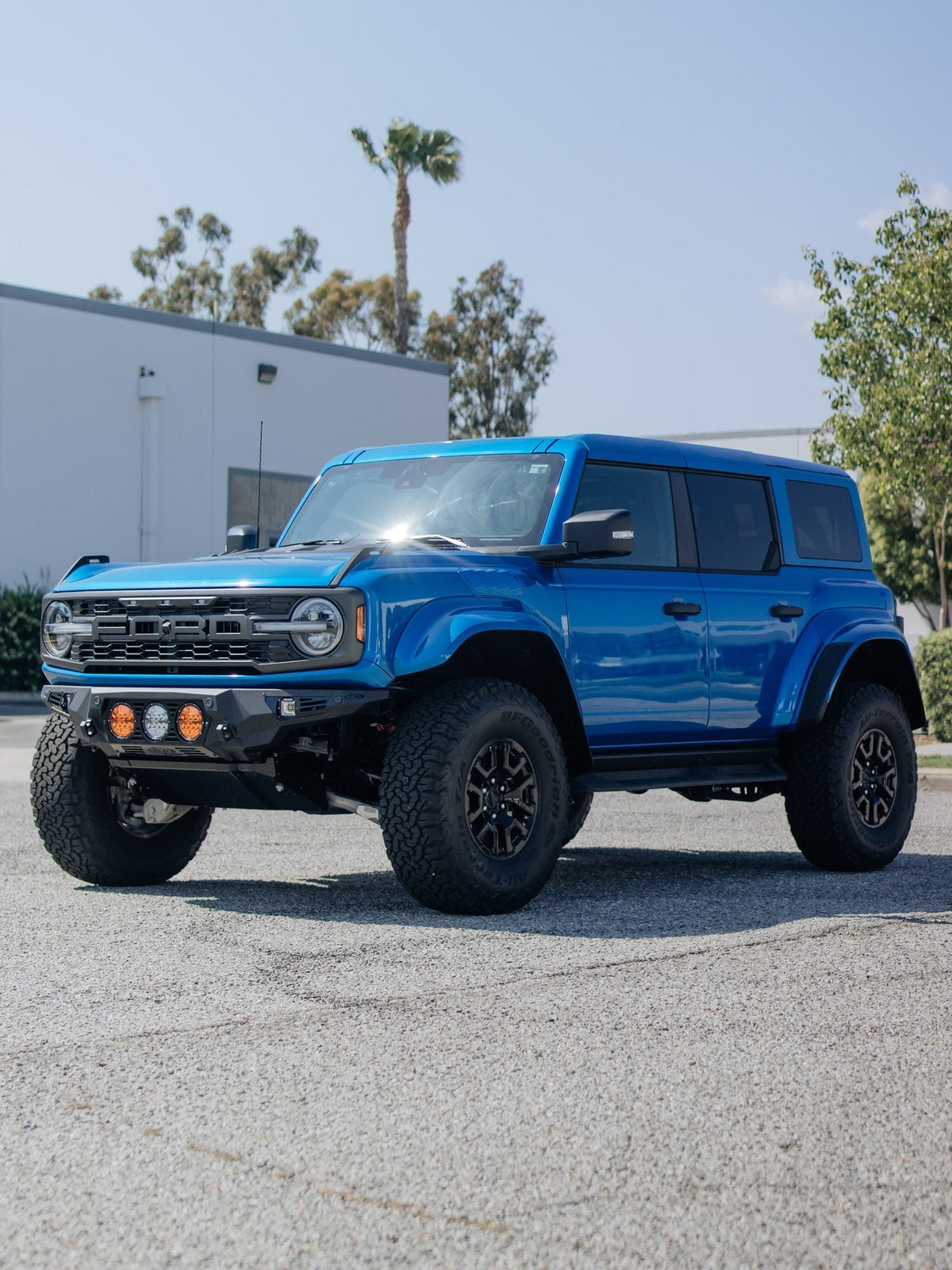 Blue Ford Bronco Raptor at a front three-quarter angle with round lights in the bumper