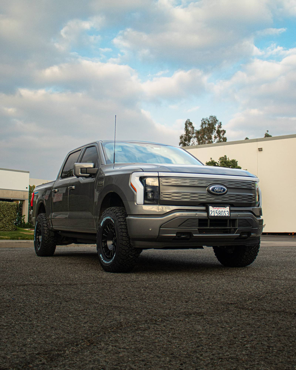Front three-quarter view of a gray Ford F-150 Lightning parked under a cloudy sky