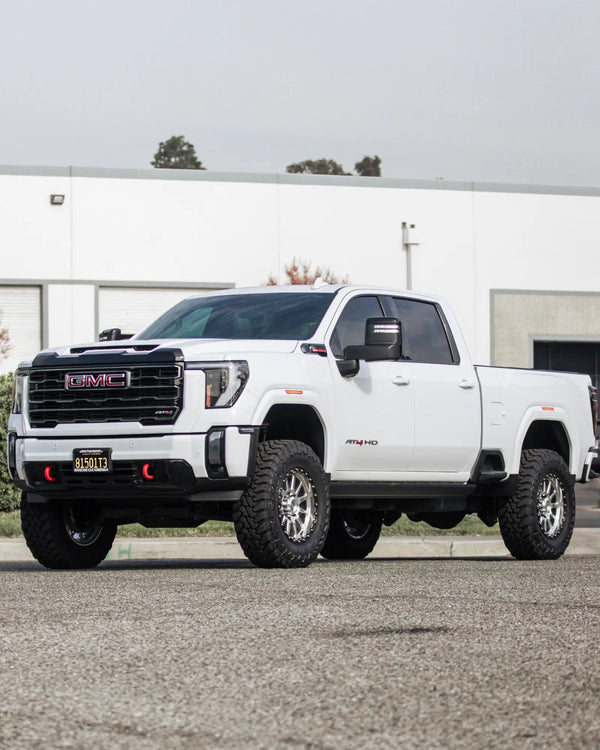 Front three-quarter view of a lifted white GMC Sierra 2500 HD AT4 with Innov8 wheels and Toyo mud-terrain tires at Empire Motorsports & LINE-X in Rancho Cucamonga