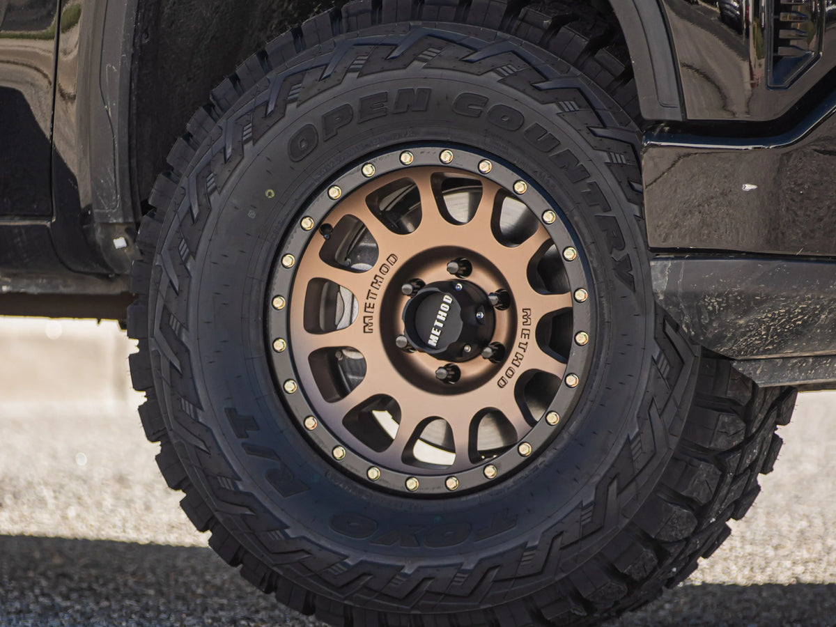 Bronze Method wheel fitted with a Toyo Open Country all-terrain tire on a black truck.