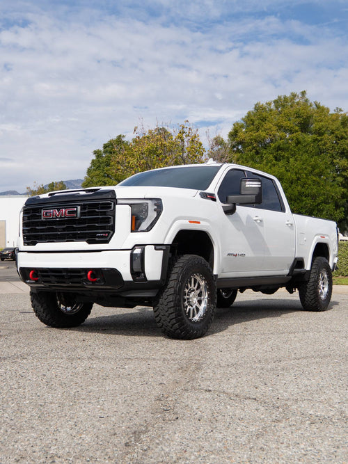 Front three-quarter view of a lifted white GMC Sierra 2500 HD AT4 with CST suspension