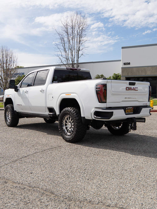 Rear three-quarter view of a lifted white GMC Sierra 2500 HD AT4 on Toyo tires