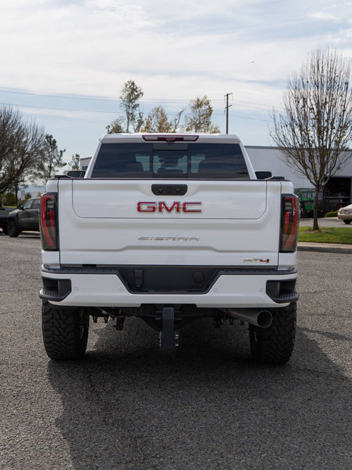 Rear view of a lifted white GMC Sierra 2500 HD AT4 with a trailer hitch