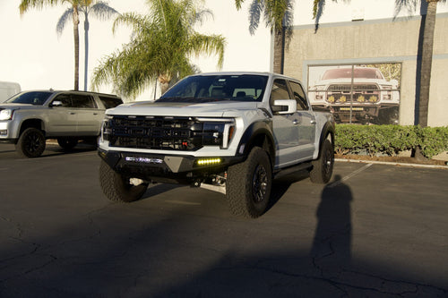 Low front three-quarter view of a silver Ford F-150 Raptor R with a lighting build