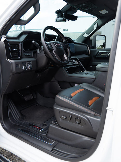 Interior of a GMC Sierra 2500 HD AT4 with black leather seats and orange accents