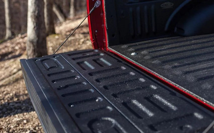 Open red pickup truck bed and tailgate protected by a glossy black LINE-X Premium spray-on bedliner.