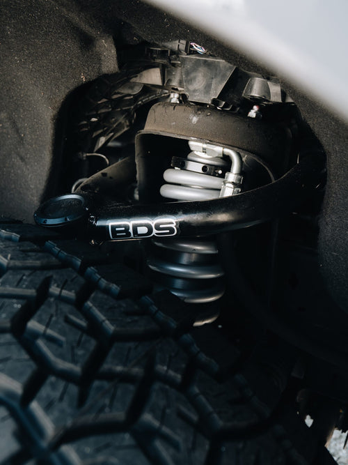 BDS upper control arm and coilover shock in the wheel well of a white truck