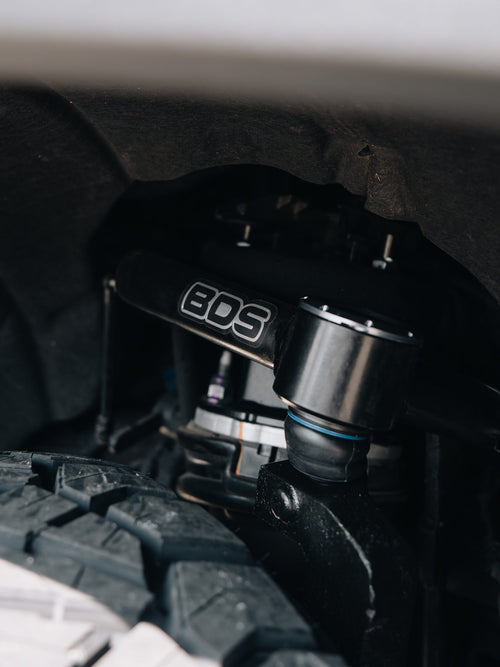 BDS coilover and upper control arm in the wheel well above the front tire of a GMC Sierra