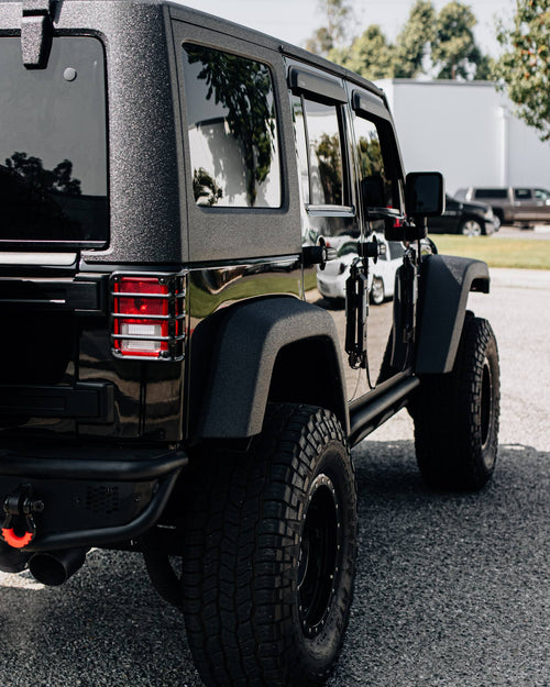 Rear fender, tail light and all-terrain tire on a black Jeep Wrangler