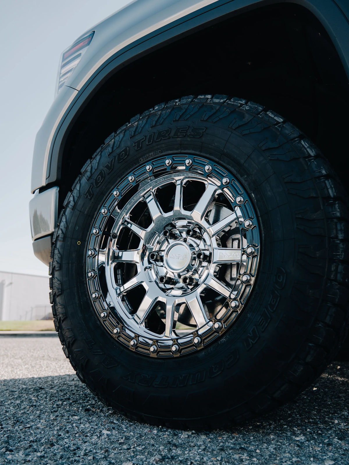 Close-up of a polished chrome multi-spoke wheel fitted with a Toyo Open Country all-terrain tire.