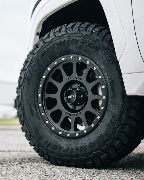 Close-up of a black wheel with an all-terrain tire on a white Toyota Tundra