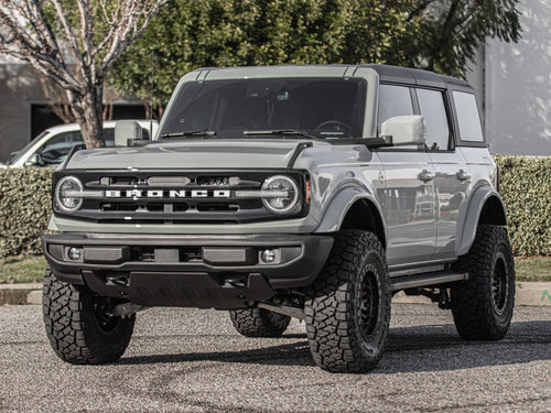 Front view of a gray Ford Bronco parked near trees