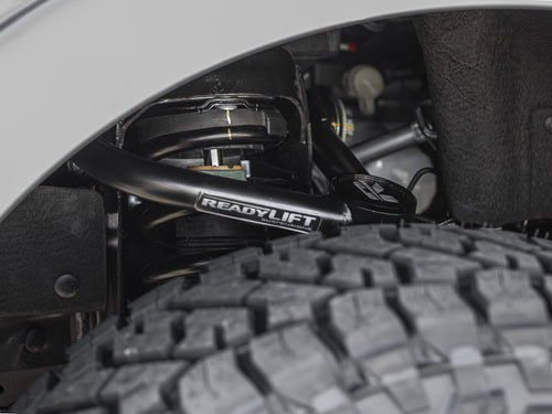 ReadyLIFT Suspensions control arm and coil spring inside the wheel well of a gray Ford Bronco