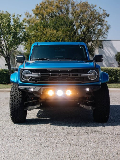 Blue Ford Bronco Raptor with its bumper lights switched on