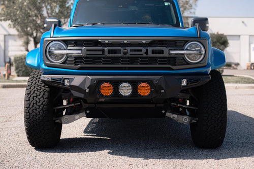 Blue Ford Bronco Raptor from the front showing its bumper-mounted round lights