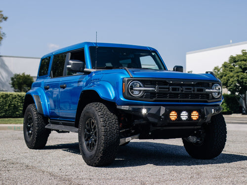 Front three-quarter view of a blue Ford Bronco Raptor with black wheels