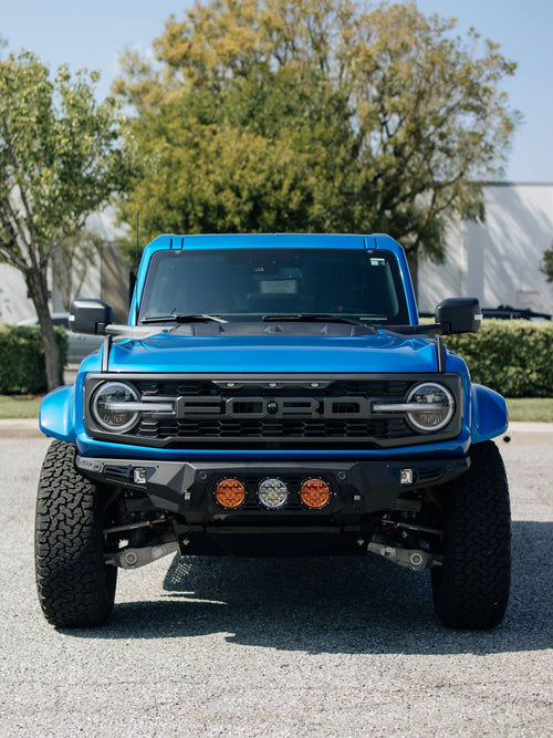 Blue Ford Bronco Raptor facing the camera with its FORD grille and bumper lights