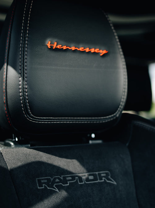 Seat headrest with orange Hennessey embroidery and a Raptor floor mat in a Ford Bronco Raptor