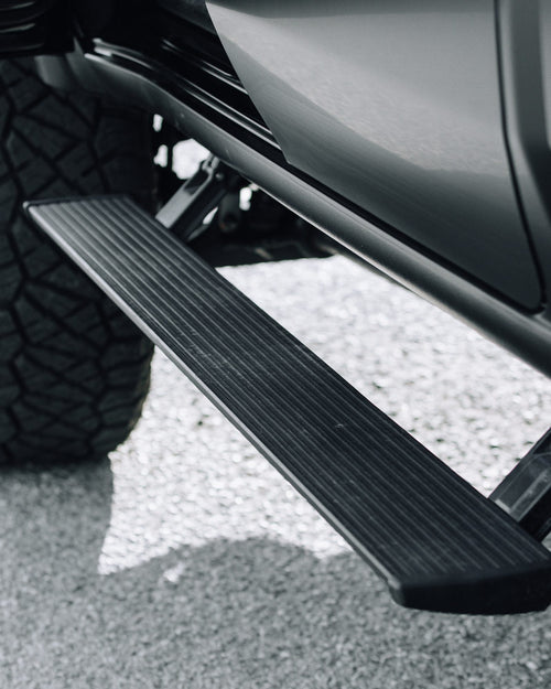 AMP Research power-retractable running board deployed on a gray Ford F-150 Lightning