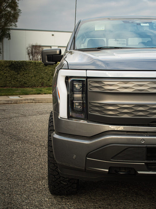 Front corner of a gray Ford F-150 Lightning with its full-width light bar
