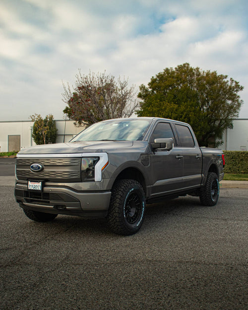 Gray Ford F-150 Lightning from a front three-quarter angle showing its light bar grille