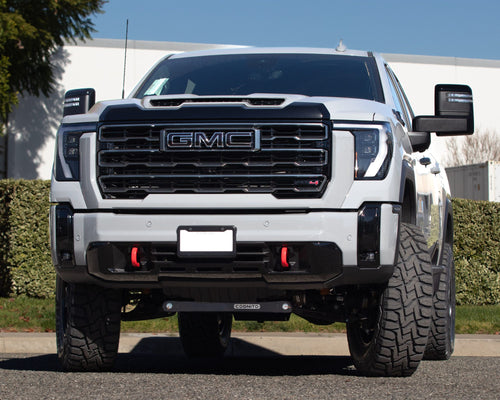 Wide front view of a silver GMC Sierra HD AT4 parked in front of a building