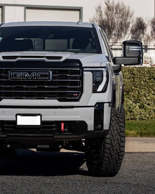 Close-up of the black GMC grille and headlight on a silver Sierra HD AT4