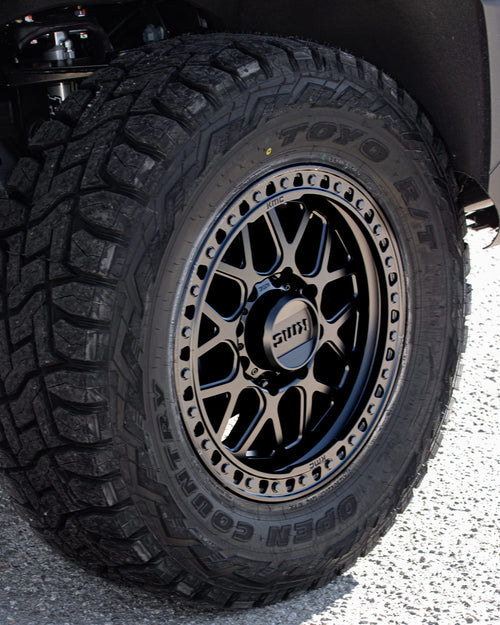 Toyo Open Country tire on a matte black KMC beadlock-style wheel on a silver GMC Sierra HD AT4