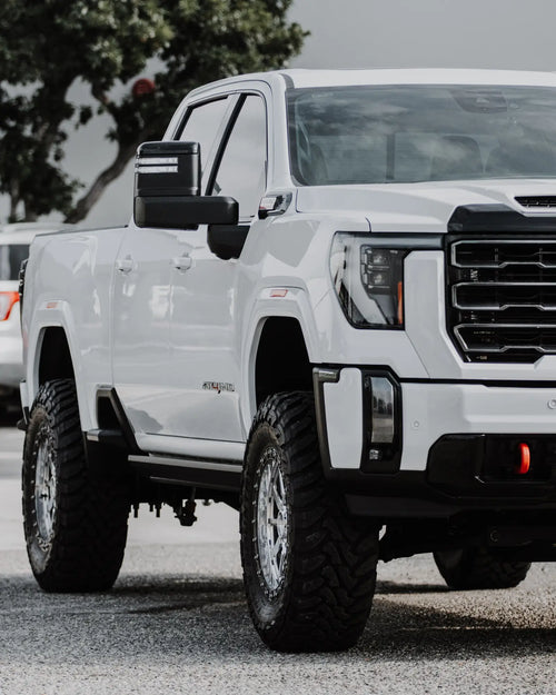 Close-up of the front fender, headlight and lifted wheel of a white GMC Sierra 2500 HD