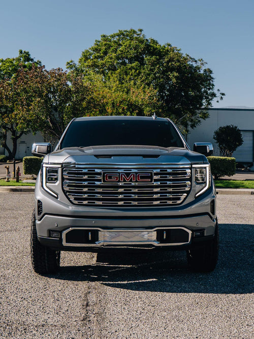 Head-on front view of a silver GMC Sierra Denali with a chrome grille and red GMC badge
