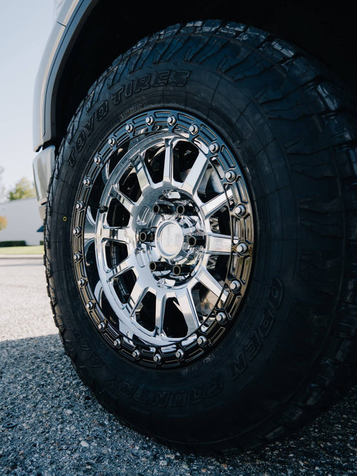 Toyo Tires Open Country all-terrain tire on a chrome wheel on a lifted silver GMC Sierra Denali