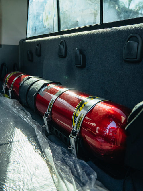 Red H3R Performance fire extinguisher strapped inside the bed of a Ram HD