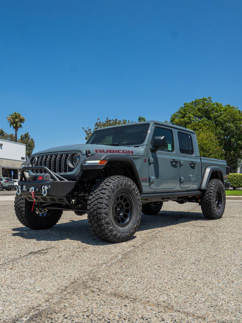 Front three-quarter view of a gray Jeep Gladiator Rubicon with a Warn winch bumper and black wheels