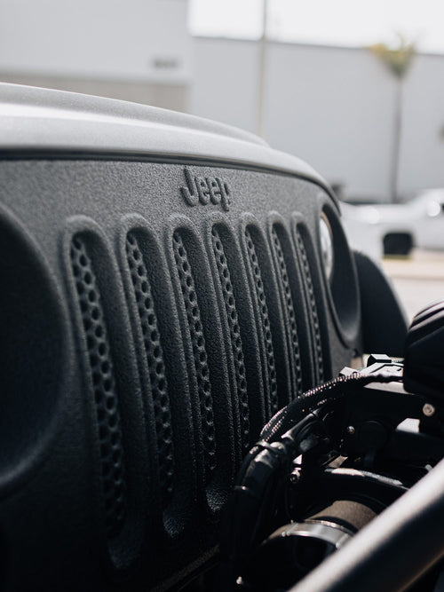 Close-up of the grille and hood of a black Jeep Wrangler