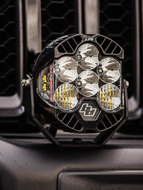Baja Designs LP6 LED light mounted at the grille of a black Jeep Wrangler Rubicon