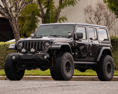 Front three-quarter view of a lifted black Jeep Wrangler Rubicon on black wheels