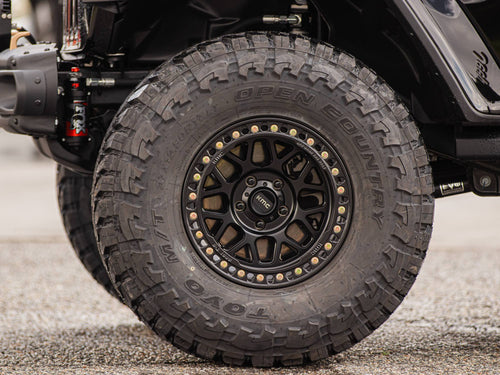 KMC beadlock-style wheel with a Toyo Open Country M/T tire and FOX shock on a black Jeep Wrangler Rubicon