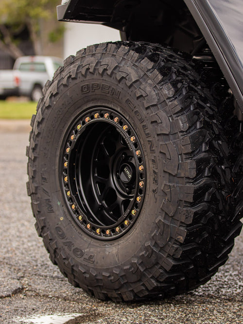 Toyo Open Country M/T mud-terrain tire tread on a KMC wheel on a black Jeep Wrangler Rubicon