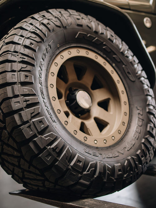 Bronze wheel with an off-road tire on a gray Jeep Wrangler Rubicon