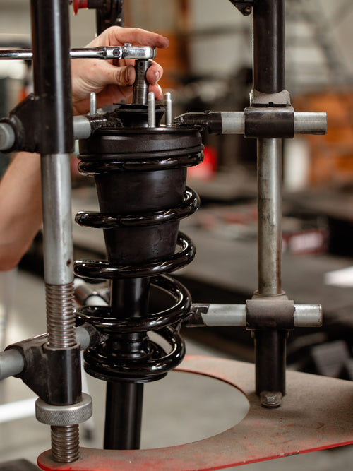 Coil spring and shock assembly displayed on a stand before installation on a Jeep Wrangler