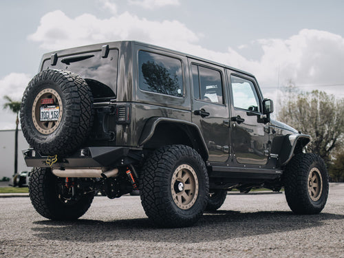 Rear three-quarter view of a gray Jeep Wrangler Rubicon with a spare tire on the tailgate
