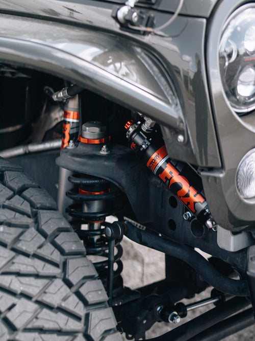Front shock, coil spring and off-road tire on a gray Jeep Wrangler Rubicon