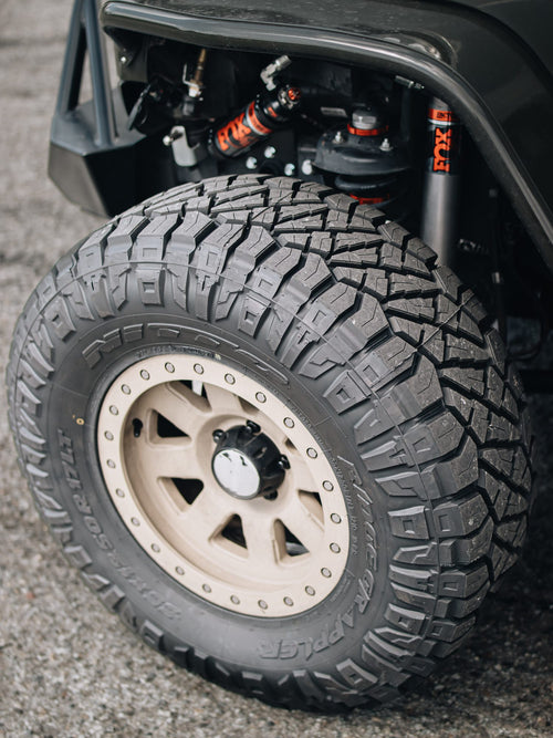Off-road tire and shock in the wheel well of a gray Jeep Wrangler Rubicon