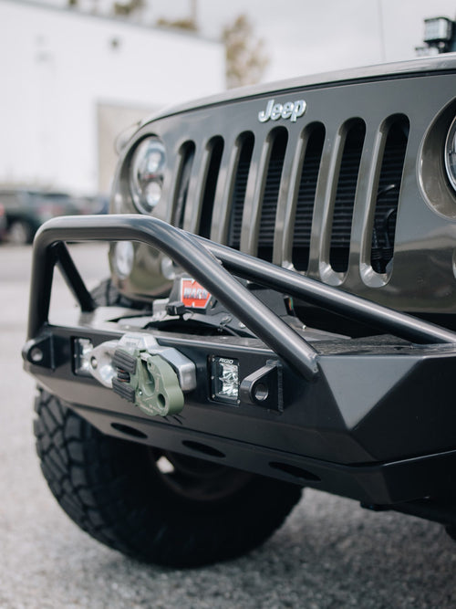 WARN winch and Rigid Industries light in the front bumper of a gray Jeep Wrangler Rubicon