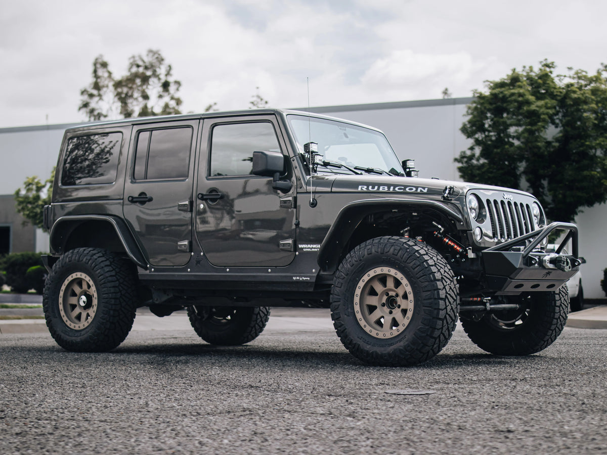 - Gray Jeep Wrangler Rubicon customized with a suspension lift, off-road wheels and tires, steel bumpers, a winch, and auxiliary lights.
