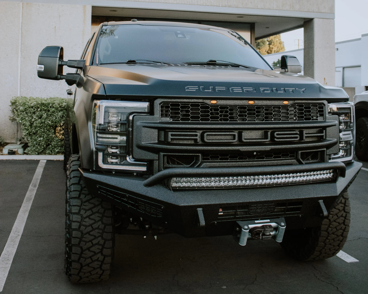 Ford Super Duty truck with a LINE-X-coated aftermarket front bumper, grille guard, LED light bar, and winch.