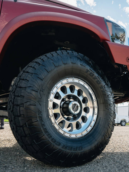 Close-up of a machined Method Race wheel with a Toyo Open Country M/T tire on a red Ram HD