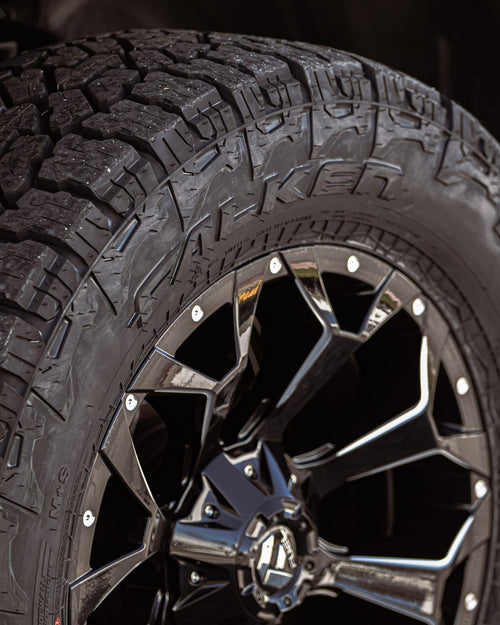 Falken Wildpeak A/T tire tread and sidewall beside a Fuel wheel on a silver RAM 1500