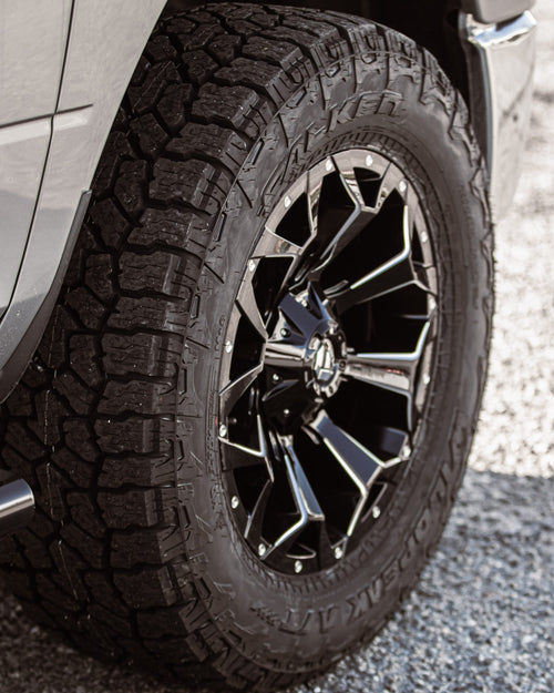 Black-and-machined wheel and all-terrain tire on a silver RAM 1500