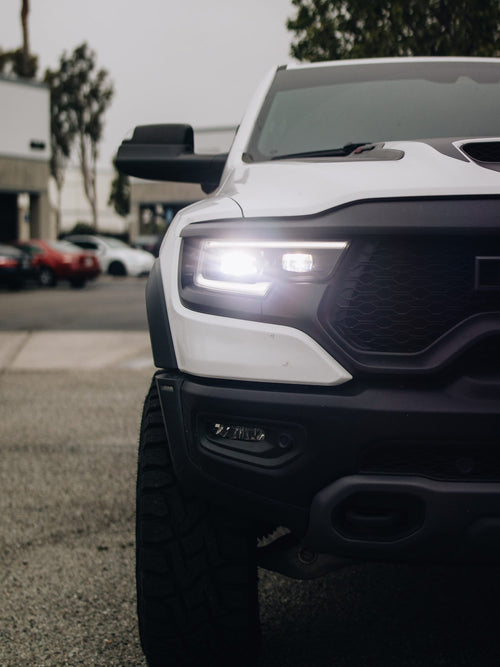 Close-up of the LED headlight on the front of a white RAM 1500 TRX